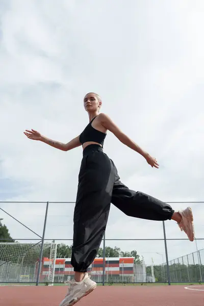 Exuberant Female Athlete Jumps Open Arms Blue Sky Showcasing Freedom Stockfoto