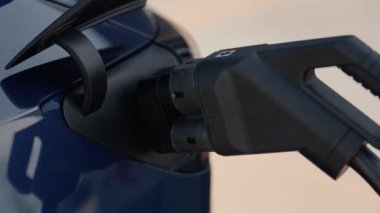 Modern sürdürülebilir ulaşım çözümlerini temsil eden mavi bir arabaya bağlı elektrikli bir aracın yakın plan görüntüsü..