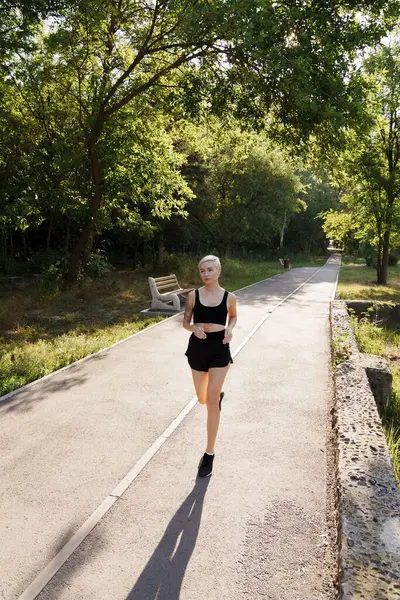 Active Young Woman Sportswear Jogs Path Leafy Park Embodying Health 图库图片