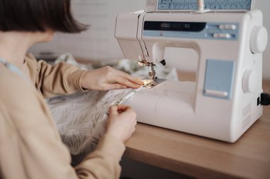 Bir makineyle kumaş dikmek, odaklanmış işçilik.