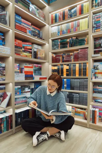 Young Woman Glasses Absorbed Reading Large Book Amidst Rows Colorful Royalty Free Stock Images