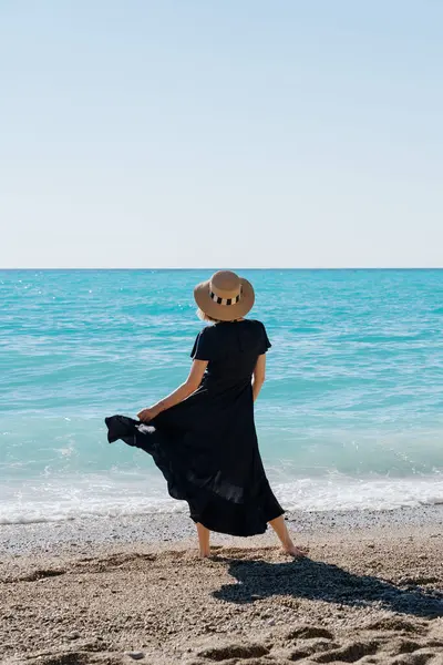 Back View Woman Black Dress Standing Beach Gazing Turquoise Sea Stock Photo