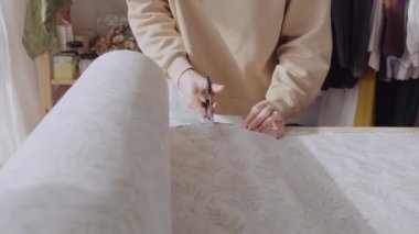 Odaklanmış kadın terzi, rahat dikiş atölyesinde desenli kumaş kesiyor..