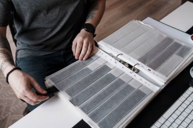 Ofis masasındaki bir klasörde sergilenen film şeritlerini dikkatle inceleyen bir insan, film fotoğrafçılığının titiz doğasını özetliyor..