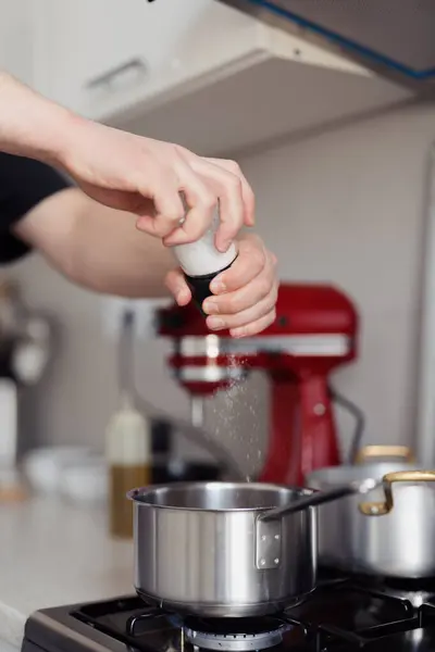 Close Hand Sprinkling Salt Pot Stove Modern Kitchen Setting Φωτογραφία Αρχείου