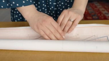 Bir kadının elleri masanın üstüne kumaş sererken, bir terzilik projesine hazırlanırken..
