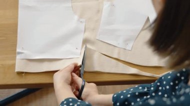 Bej kumaşı makasla kesen terzilerin yakın çekim görüntüsü, kıyafet oluşturmaya odaklanma.