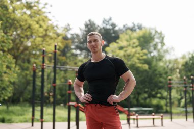 Spor giyim sektöründe kaslı bir adam açık hava fitness parkında egzersiz yaptıktan sonra sağlıklı bir yaşam tarzı ve spor yapmaya kendini adamış..