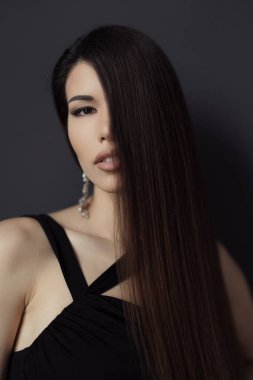 Şık siyah elbiseli sofistike bir kadının portresi. Parlak, uzun esmer saçlar ve ince bir omuz ve sırt işareti..