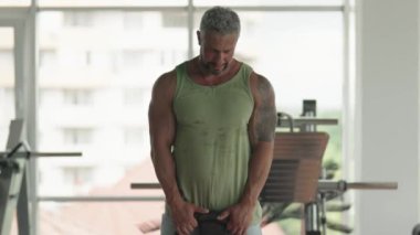 Modern bir spor salonunda ağırlık kaldıran bir adam. Güç, kararlılık ve zindelik göstergesi. Fitness, sağlık ve yaşam tarzı kavramları için uygundur..