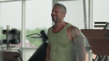 Formda adam spor salonunda çalışırken dambıl kaldırıyor. Güç eğitimine ve fiziksel kondisyonuna odaklan..