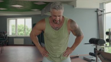 Formda adam spor salonunda ısınma egzersizleri yaparak güç antrenmanına hazırlanıyor. Odaklanmış ve spor yapmaya hazır görünüyor..
