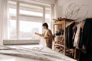 Parlak dikiş atölyesinde giysiler tasarlayan odaklanmış bir kadın..