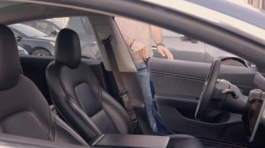Bir adam arabaya binmeye hazırlanıyor emniyet kemerini sıkıca bağlıyor ve yola koyuluyor. Düşünceli araç güvenliği ve yolculuk hazırlığı tasvir edilmiştir..