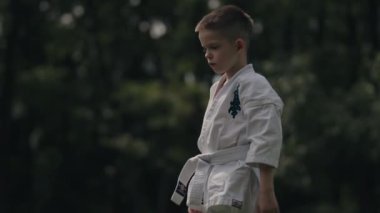 Bir anne ve oğlu dışarıda karate çalışıyor. Beyaz karate üniformaları giyiyorlar ve hareketlerine odaklanmış durumdalar. Videoda huzur, disiplin ve bağlanma duygusu var..