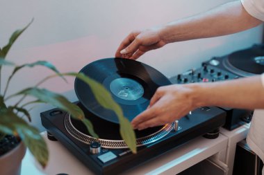 DJ turntable 'a vinil plak koyarak müzik yapmaya hazırlanan kişi.