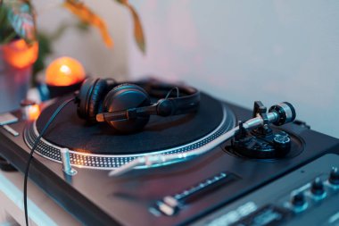 Kulaklıklı bir DJ pikabının yakın çekimi, müzik prodüksiyonunun özünü yakalıyor..