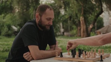 İki arkadaş parktaki bankta satranç oynamaktan zevk alıyor. Hareketlerine odaklanmış ve stratejik davranıyorlar..