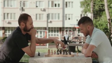 Güneşli bir günde iki arkadaş parkta satranç oynamaktan zevk alır. Hareketlerine odaklanmış ve stratejik davranıyorlar..