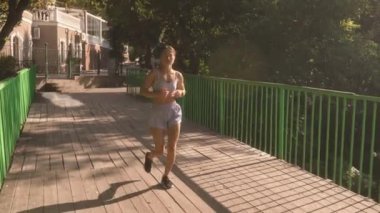 Sabahları parkta koşan genç bir kadın. O mutlu ve aktif yaşam tarzından hoşlanıyor. Güneşli bir yaz gününde çekilmiş..