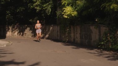 Genç bir kadın güneşli bir günde şehirde koşuya çıkar. Spor kıyafetleri ve koşu ayakkabıları giyiyor. Bu video sağlık, zindelik, kentsel yaşam ve egzersiz konularını çağrıştırıyor.