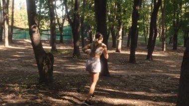 Genç bir kadın, sağlıklı ve aktif bir yaşam tarzını kucaklayarak güneşli bir parkta koşmaktan hoşlanıyor..