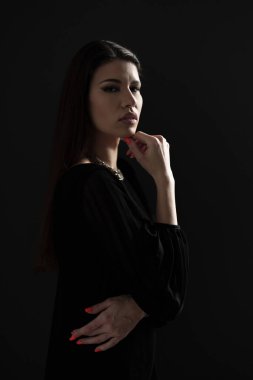 Zarif, siyah bir kadın eli kalçasında poz veriyor, koyu bir arka plana çarpıcı kırmızı oje sürüyor, sofistike ve stil yayıyor..