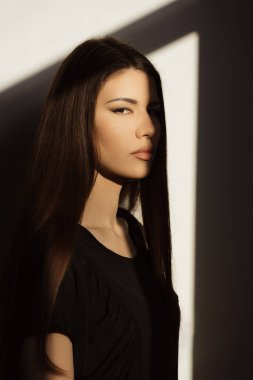 Çelişkili gölgeler arasında yakalanmış zarif bir kadının çarpıcı portresi. Bakışları yoğun ve ışıklandırma, çarpıcı ve sofistike bir görünüm yaratarak onun özelliklerini vurguluyor..