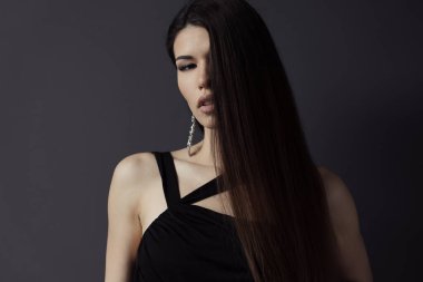 Yan görüntüde yakalanan isimsiz bir kadın, zarif siyah akşam elbisesini gösteriyordu. Küpesinden gelen hafif bir parıltı, esrarengiz, karanlık bir arka plana doğru..