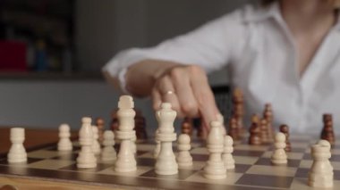 Beyaz gömlekli bir iş kadını satranç oyununda stratejik bir hamle yapar. Zekasını ve kararlılığını gösterir..