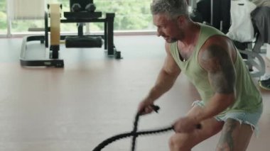 Spor salonunda halat egzersizi yapan bir adam. Güç antrenmanı, fitness ve fiziksel kondisyona odaklanmış..