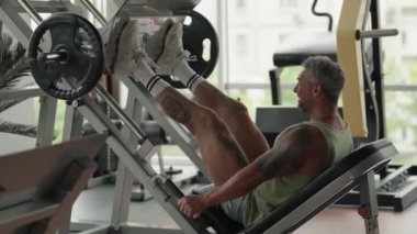 Spor salonunda bacak presi makinesinde çalışan bir adam. Güç antrenmanına ve fitness 'e odaklan. Sağlıklı yaşam tarzı kavramı.