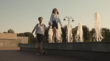 Şehir parkında bir çeşmenin yanında yürürken el ele tutuşan romantik genç bir çift. Mutlular ve birlikte vakit geçiriyorlar..