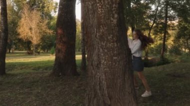 Güneşli bir parkta el ele tutuşan genç bir çift. Ağaçların arasında yürürken yaz havasının tadını çıkarıyorlar..