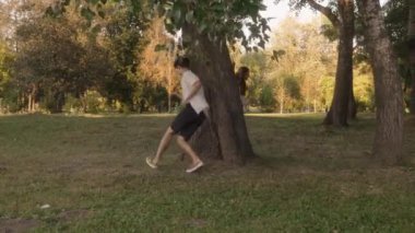 Genç bir adam ve kadın parkta kovalamaca oynuyorlar. Ağaçların etrafında koşuyorlar ve eğleniyorlar. Güneş batıyor, sıcak ve mutlu bir atmosfer yaratıyor..