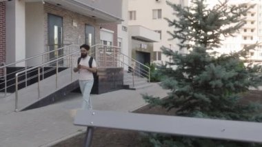 Genç bir adam akıllı telefonunu kullanarak caddede yürür. Binalar ve ağaçlar arasında gezinirken mesajları kontrol ediyor..