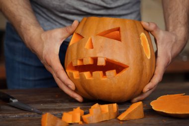 Balkabağından garip bir balkabağı kabağı oyan ellerin yakın çekimi. Cadılar Bayramı süslemeleri ve şenlikli sonbahar aktiviteleri için mükemmel..