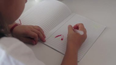 Genç bir kız kırmızı kalemli bir defter çiziyor..