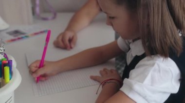 Beyaz bir masada oturan iki genç kız, derslerine odaklanmış..