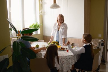 Bir aile bir mutfak masasının etrafında toplanır ve birlikte kahvaltı ederler. Çocuklar okula hazırlanırken ortam hareketli ve neşeli. Bir anne çocuklarıyla mutlu mesut meşgul olur..