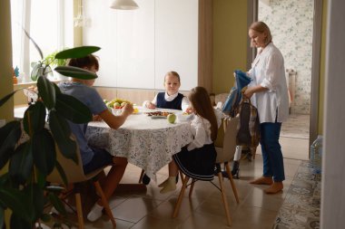 Bir aile kahvaltı için yemek masasının etrafında toplanır ve onlar okula hazırlanırlar. Sahne, güne sıcak ve düzenli bir şekilde başlıyor..