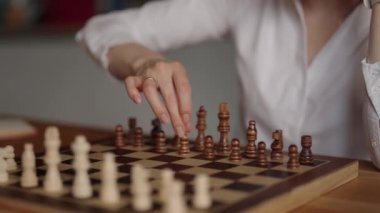 Beyaz gömlekli odaklanmış bir iş kadını satranç oynarken bir sonraki hamlesini düşünüyor. Temalar arasında strateji, iş ve eğlence yer alıyor.