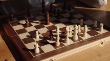 Beyaz gömlek giyen bir iş kadını kendi ofisinde tek başına satranç oynar. Beyaz vezir satranç taşını gün boyunca tahtada oynatıyor..