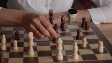 Beyaz gömlek ve saat giyen bir iş kadını bir sonraki hamlesini bir satranç maçında düşünürken düşüncelere dalıyor. Bu strateji oyununda kendine karşı oynuyor..