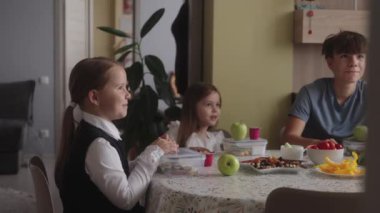 Mutfakta sağlıklı yemek yiyen mutlu çocuklar. Aile okul için hazırlanıyor. Erkek ve kız kardeşler okuldan önce kahvaltı ederler. Çocuklar için sağlıklı yiyecekler.