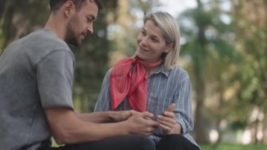 Kadın ve erkek cep telefonuna bakıp gülümsüyor. Onlar parkta oturuyorlar. İyi haberleri paylaşmak mı yoksa birlikte komik bir şeyler izlemek mi?.