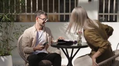 Bir erkek ve bir kadın açık bir kafede oturup dostça bir iş görüşmesi yapıyorlar. Planları ve fikirleri gün ışığında tartışıyorlar..
