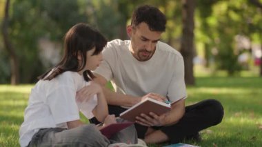 Şefkatli bir baba kızına parkta ders çalışmasında yardımcı olur. Kitaplarla ve öğrenmeyle bağ kurarlar..