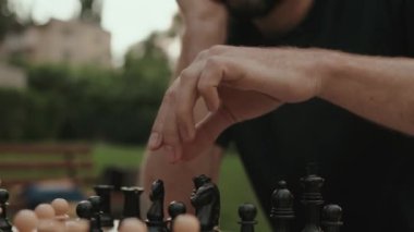 Parktaki bir satranç oyununda bir sonraki hamlesini düşünürken bir erkeğin ellerine yaklaş. Yönetim kurulunu analiz ederken stratejik düşünce ve konsantrasyon çok açık.