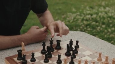 Satranç oyununda hamle yapan bir adamın ellerini yakından çek. O bir parkta oynuyor..